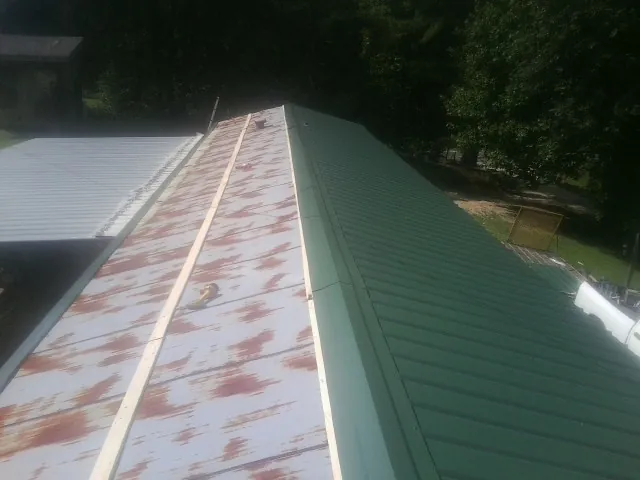 Old rusted panels beside newly installed green metal roofing — Wind Damage Roof Repair by Roofing Brothers in Mechanicsville