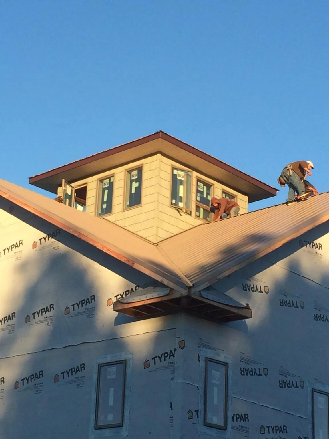 Roofers working around a rooftop cupola on a new metal roof at sunset — Roof Waterproofing in Mechanicsville by Roofing Brothers